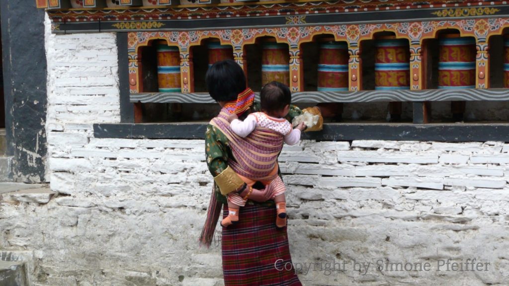 Prayer wheels in Mongar Dzong. www.explorations-travel.vom Frau an den Gebetsmühlen im Mongar Dzong.